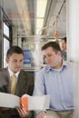 Men looking at file on train Royalty Free Stock Photo