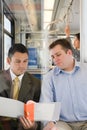 Men looking at file on train Royalty Free Stock Photo