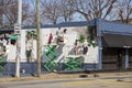 men painting a wall mural on the side of a restaurant with bare winter trees and a gorgeous blue sky in Atlanta Georgia
