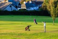 Men playing golf in low bright evening sunlight