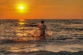 Men playing water at the beach with sunset.