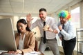 Men popping paper bag behind their colleague in office. Funny joke