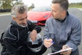 Men on race track in front sports car