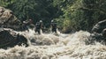 Men rafting in swift rapids with equipment among rocks, AI-generated.