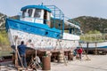 Men repairing and painting old large boat