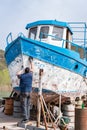 Men repairing and painting old large boat