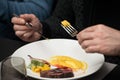 Men in a restaurant eating medium grilled cut pork steak with blood on the plate with parsnip puree and corn