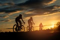 The men ride bikes at sunset with orange-blue sky background. Royalty Free Stock Photo