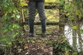 Men in rubber boots on the rustic wooden bridge in the forest