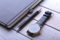 Men`s accessories for business and rekreation. Leather notebook, watch and pen on wood background.. Top view composition.