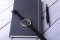 Men`s accessories for business and rekreation. Leather notebook, watch and pen on wood background.. Top view composition. Royalty Free Stock Photo