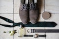 Men`s accessories on the floor. Composition of shoes, tie, belt, wrist watch, perfume bottle and groom`s boutonniere.