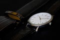 Men`s accessories - a vintage mechanical watch and a black leather belt lie on a dark background. The trend is in black. Selectiv