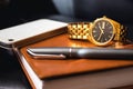 Men's accessory, golden watch, pen and mobile phone on the leather diary.