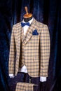 Men`s business suit on mannequin, vintage color. elegant sand-colored three-piece suit in a cage with a bow tie and a