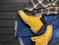 Men`s casual wear, yellow work boots from natural nubuck leather, blue jeans, checkered shirt and brown belt on dark wooden Royalty Free Stock Photo