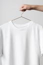 Men`s Crew Neck T-Shirt Mock-Up - Man holding a white t-shirt on a copper wire clothes hanger