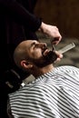 Men`s fashion. The barber scissors beard of brutal man in the stylish barbershop