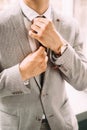 Men`s fashion. Handsome man wearing stylish suit and wristlet watch straightens a tie