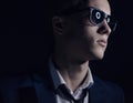 Men's fashion theme: handsome young man in a stylish suit and sunglasses standing on a dark background in the studio Royalty Free Stock Photo