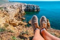 Men`s feet with sneakers on the background of a stunning landscape with turquoise sea and rocks, Crimea