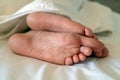 Men`s feet under a white blanket. Sleeping man under a white blanket Royalty Free Stock Photo