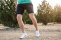 Men`s feet in white sneakers running over rough terrain. Cross country running with focus on runner`s legs