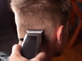 Men haircut, master cuts r a young guy with a hair clipper closeup, hairdresser tool