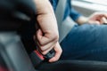 Men`s hand fastens the seat belt of the car.