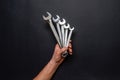 Men`s hand holding set of wrenches on black background. Tools in human hand. Man worker with spanners. Technique repair, equipmen Royalty Free Stock Photo