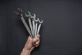 Men`s hand holding set of wrenches on black background. Tools in human hand. Man worker with spanners. Technique repair, equipmen Royalty Free Stock Photo