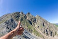Men`s hand pointing his finger up against the mountain peaks Royalty Free Stock Photo