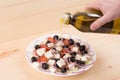 Men`s hand pouring olive oil into Greek salad. Wooden background Royalty Free Stock Photo