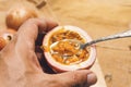 men's hand scooping out pulp and seeds from passion fruit .