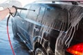 Men's hand wash dirty SUV by high pressure wash. Touchless car wash self-service in the open air. Contactless car wash self-servi Royalty Free Stock Photo