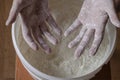 Men`s hands brushed with white flour, plastic bucket with wheat flour in the background