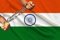 Men`s hands chained in heavy iron chains against the background of the flag of India on a gentle silk with folds in the wind, the Royalty Free Stock Photo