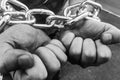 Men's hands are chained in thick steel shackles