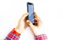 Men`s hands in a checkered hipster shirt are holding a smartphone on a white background. The screen is white and black. Hands Royalty Free Stock Photo
