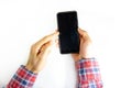 Men`s hands in a checkered hipster shirt are holding a smartphone on a white background. The screen is white and black. Hands Royalty Free Stock Photo