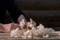 Men`s hands close-up planing a classic wooden plane board on a workbench with a pile of shavings on the background of a dark wall