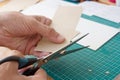 Men`s hands are cutting craft cardboard with scissors. Production of handmade jewelry