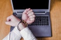 Men`s hands handcuffed on a laptop.