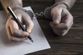 Men`s hands with handcuffs fill the police record, confession.