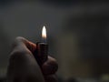Men`s hands hold lighters, fire from cigarette. Burning lighter in a man`s hand. Blue flame of a lighter. The texture of the ski