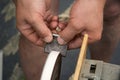 Men`s hands hold a piece of metal, which is sharpened with the help of a grinding electric circle