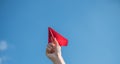 Men`s hands hold a red paper rocket with a bright blue background Royalty Free Stock Photo