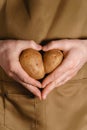 Men`s hands hold ugly potatoes in the shape of a heart