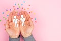 Men`s hands holding a couple of gay men cut out of paper on a pink background. Valentine`s Day, gay pride day. Lgbt concept