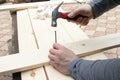 Men`s hands holding a hammer. A hammer striking a nail on a wooden table